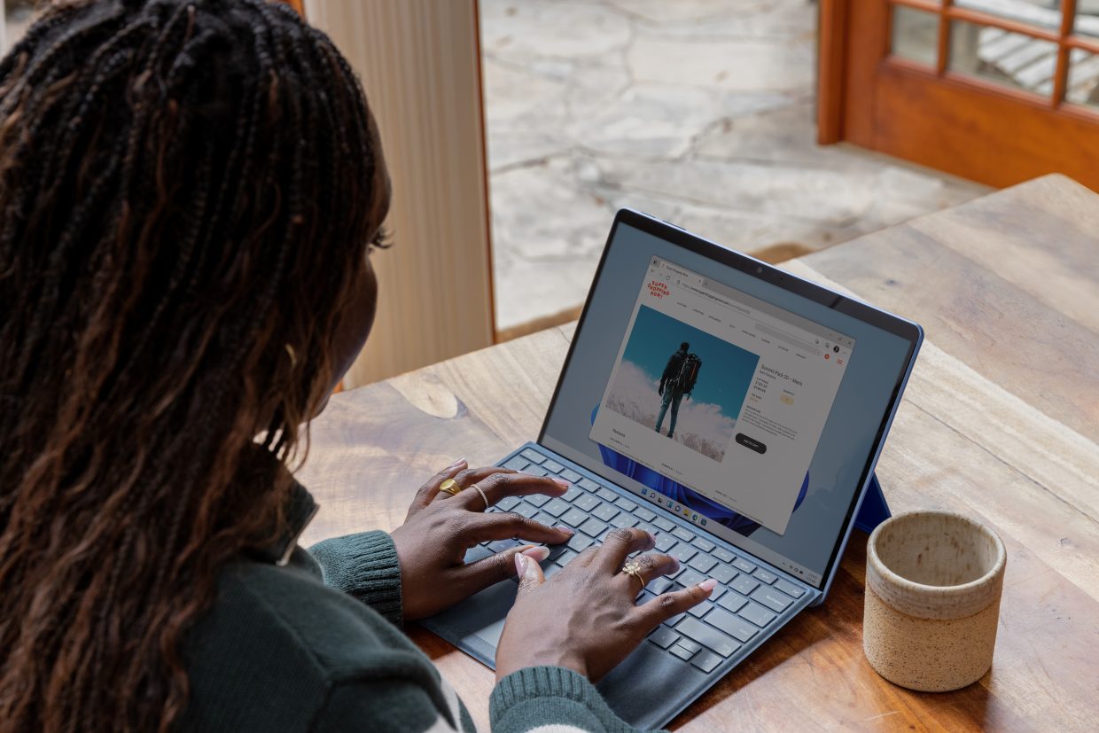 A woman seated at a desk working on a laptop with a mug of coffee beside it.